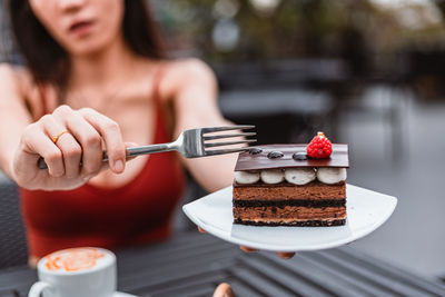 Midsection of woman holding ice cream on table