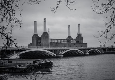 Boat moored on river by battersea power station against sky