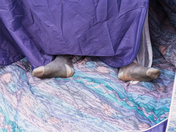 From above of unrecognizable traveler in socks resting in tent in daytime at campsite person