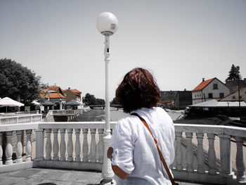 Rear view of woman standing on street against clear sky