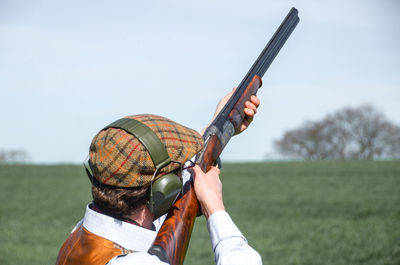 Rear view of man holding gun on field