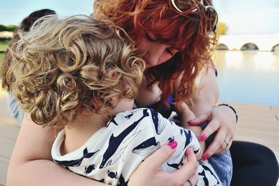 Close-up of woman holding son on pier over lake