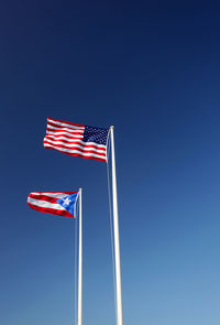 Low angle view of flag flags against clear blue sky