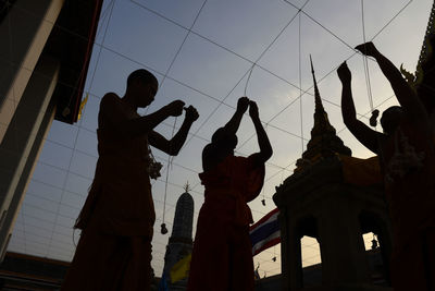 Low angle view of silhouette people decorating temple