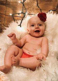 High angle portrait of cute shirtless baby girl lying on rug