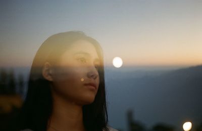 Portrait of young woman looking at camera against sky