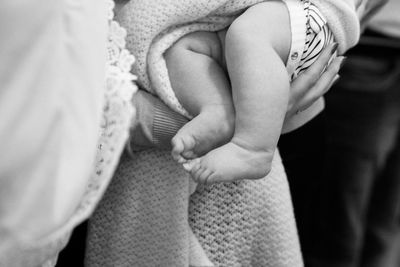 Midsection of mother carrying baby at home