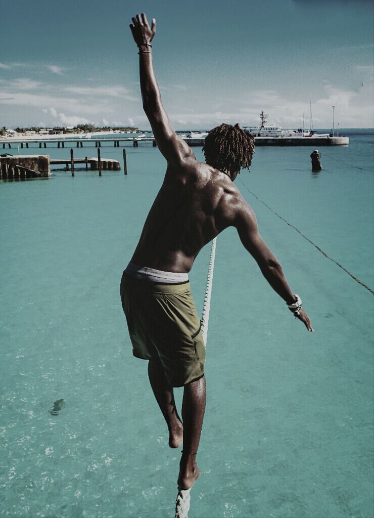 full length, water, lifestyles, leisure activity, sky, sea, jumping, casual clothing, standing, rear view, enjoyment, men, person, fun, arms outstretched, holding, arms raised, shirtless