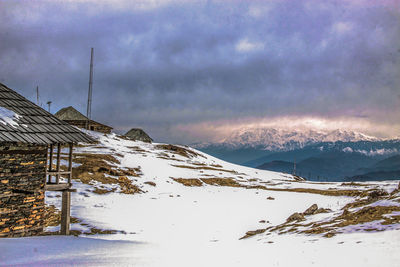 Scenic view of snow covered mountains against cloudy sky