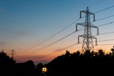 Low angle view of silhouette electricity pylon against sky at sunset