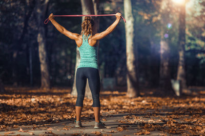 Rear view of female athlete exercising with resistance band at park