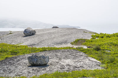 Stone wall by rocks against sky