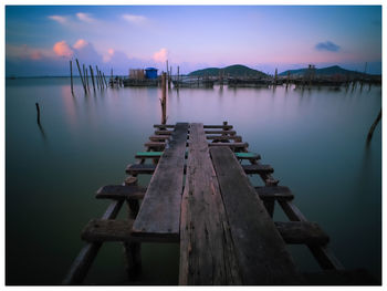 Pier over lake against sky during sunset