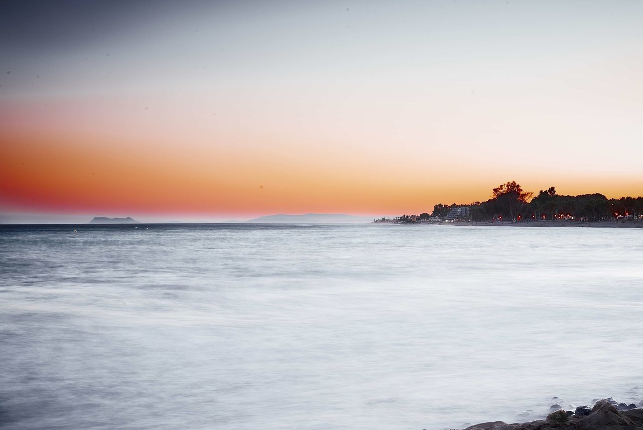 sea, water, sunset, horizon over water, scenics, tranquil scene, beauty in nature, built structure, tranquility, architecture, waterfront, sky, orange color, building exterior, copy space, beach, nature, clear sky, idyllic, shore