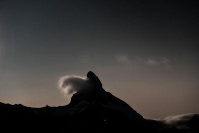 Low angle view of silhouette people on mountain against sky at night