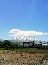 Houses on field by buildings against sky