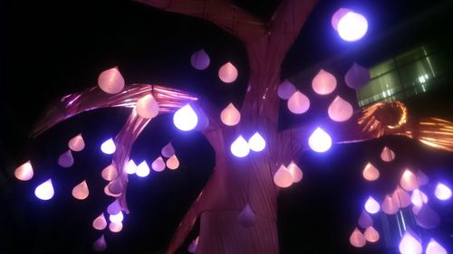 Low angle view of illuminated lighting equipment at night