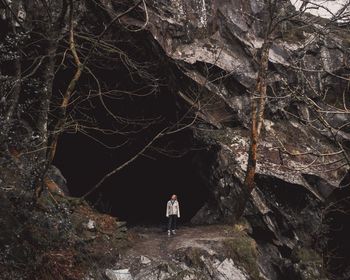 Woman standing against entrance of cave