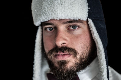 Close-up portrait of mid adult man against black background