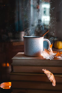 Stacked books and hot tea against rainy window