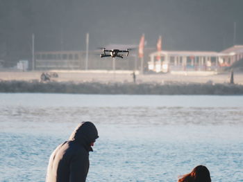 Man flying over sea against sky