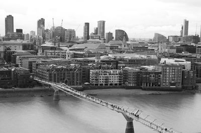 Modern buildings by river against sky in city