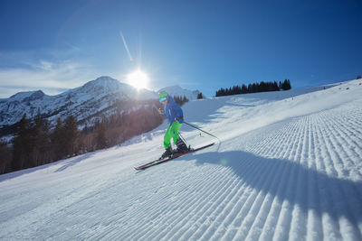 Rear view of man skiing on snow covered mountain against sky