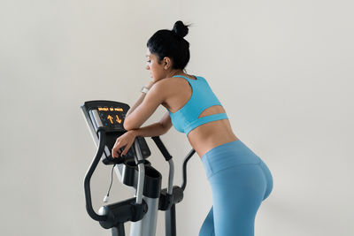 Young woman training at the gym using eliptical crosstrainer