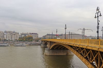 Bridge over river in city against sky