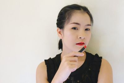 Portrait of young woman with lipstick against wall