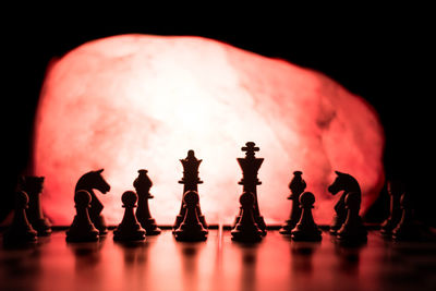 Close-up of silhouette chess pieces in darkroom