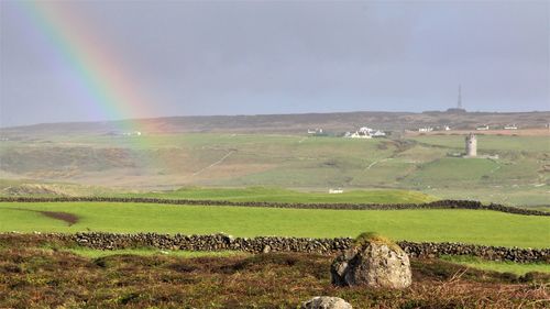 Scenic view of field against rainbow in sky