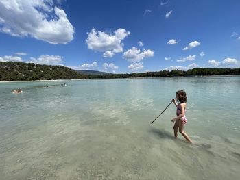 Full length of man standing on shore at beach against sky