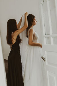 A bridesmaid helps the bride put on her veil.