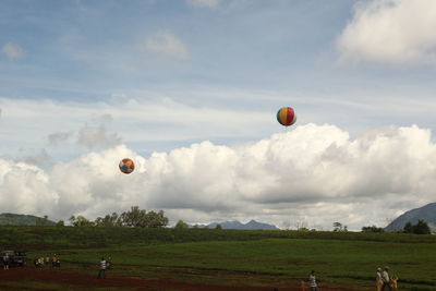 Hot air balloon flying over grassy field