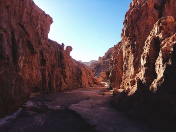 Empty road amidst rock formations against clear sky