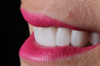 Close-up of woman with pink petals against black background