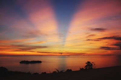 Scenic view of sea against dramatic sky during sunset