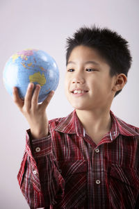 Smiling boy holding globe against white background