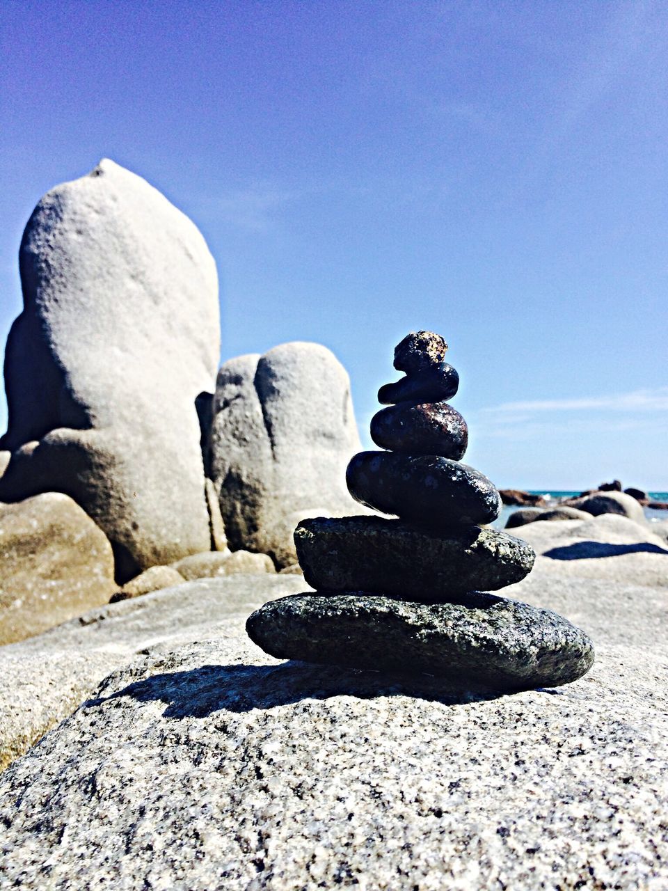 rock - object, sunlight, tranquility, stack, blue, sky, stone - object, tranquil scene, beach, clear sky, balance, sand, stone, shadow, nature, rock formation, day, scenics, rock, sculpture