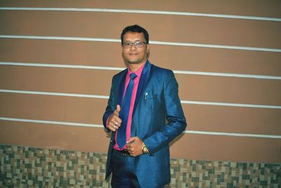 Portrait of young man standing against wall