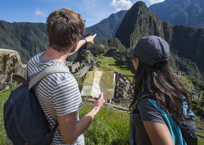 Couple at inca ruins looking at folding map, machu picchu, peru