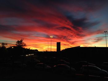 Silhouette of factory against sky at sunset