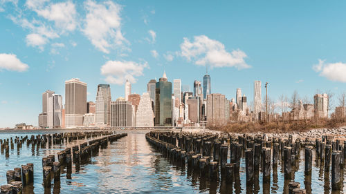 View of mooring post with cityscape against cloudy sky