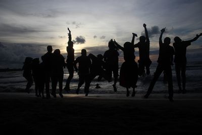 Silhouette people at beach against sky during sunset