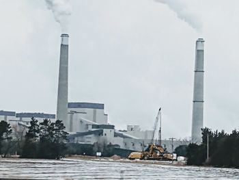 Smoke emitting from factory against sky