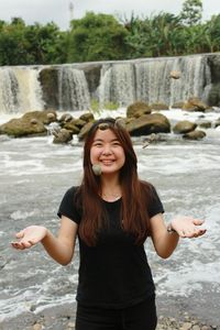 Young woman standing against waterfall