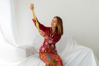 Malay lady, long hair, celebrates ramadan, in red kebaya, holding ketupat food, white background