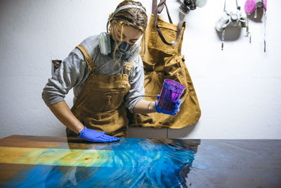 Female resin artist working with her hands on large artwork