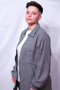 Portrait of young woman standing against white background